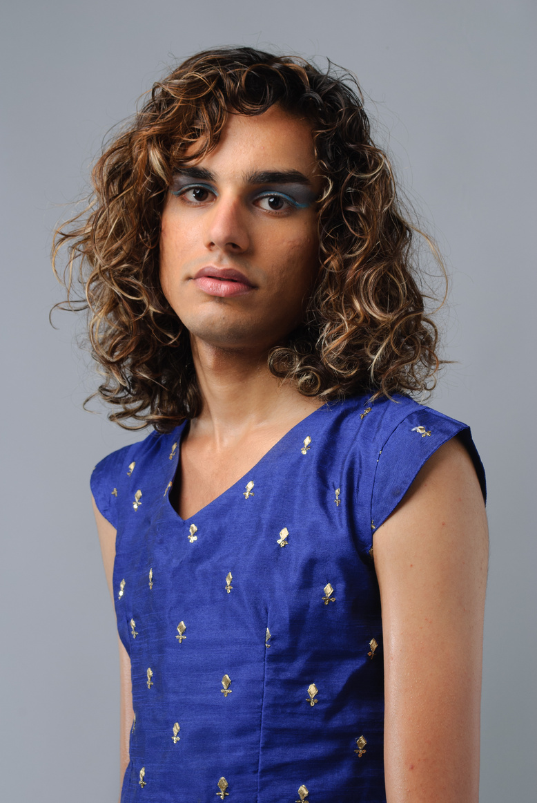 mayed is a brown, queer, Muslim with black curly hair and blonde highlights. mayed is looking directly at the camera, wearing a blue choli and matching eye makeup